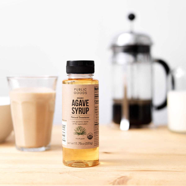 bottle of organic agave syrup, french press coffee maker, glass of coffee, wooden table