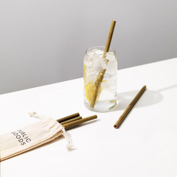 public goods branded cotton pouch with bamboo straws, bamboo straw in glass of ice water with lemon, tabletop