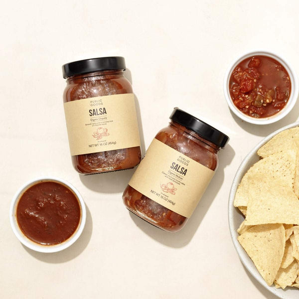 two jars of salsa, bowl white corn tortilla chips, salsa