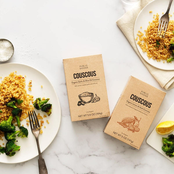 two boxes of public goods couscous, two plates with couscous and broccoli, salt, lemon