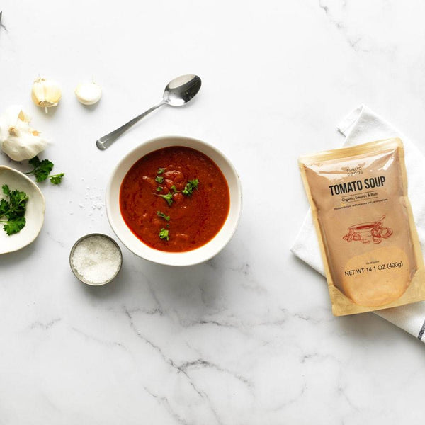 bowl of tomato soup, bag of public goods organic tomato soup, salt, spoon, garlic, herbs